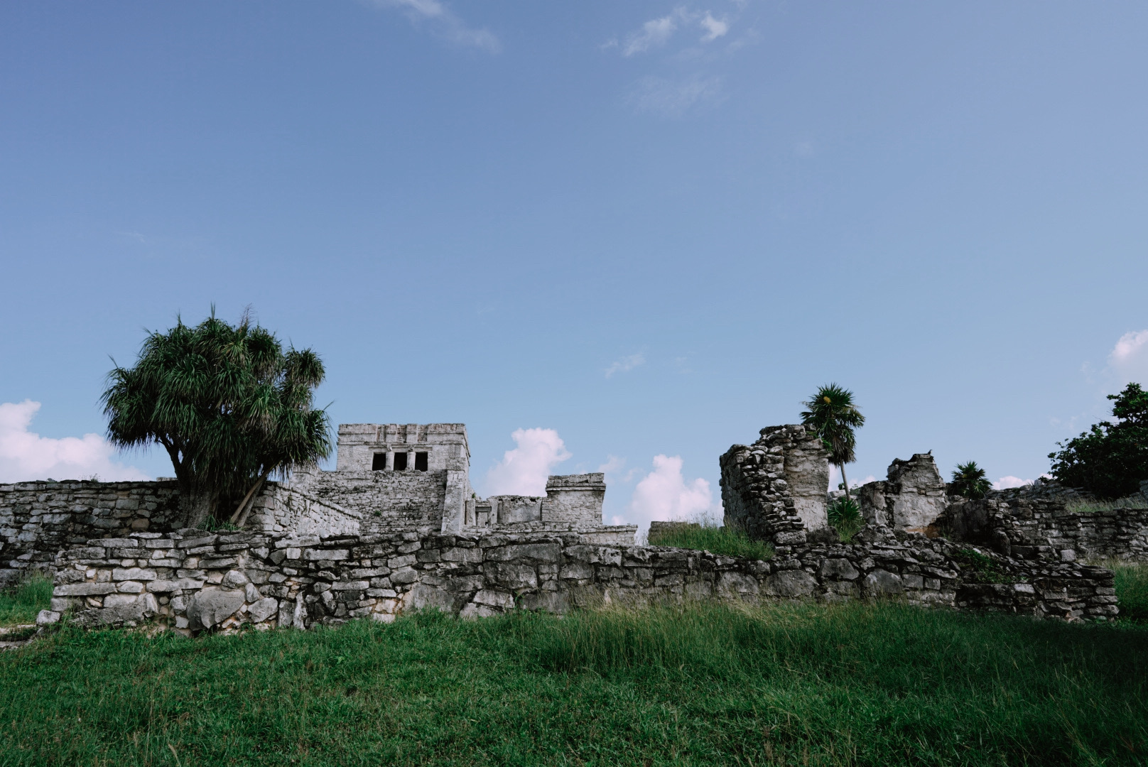 Historic stone wall and green grounds at the Tulum Ruins