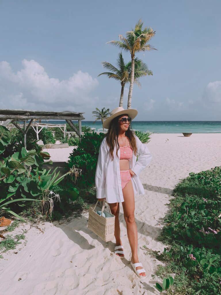 Woman in bikini and cover-up on a luxury Tulum beach, ready for a wellness getaway