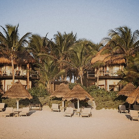 Luxury Tulum accommodations: beachfront bungalows with thatched roofs and palm trees.