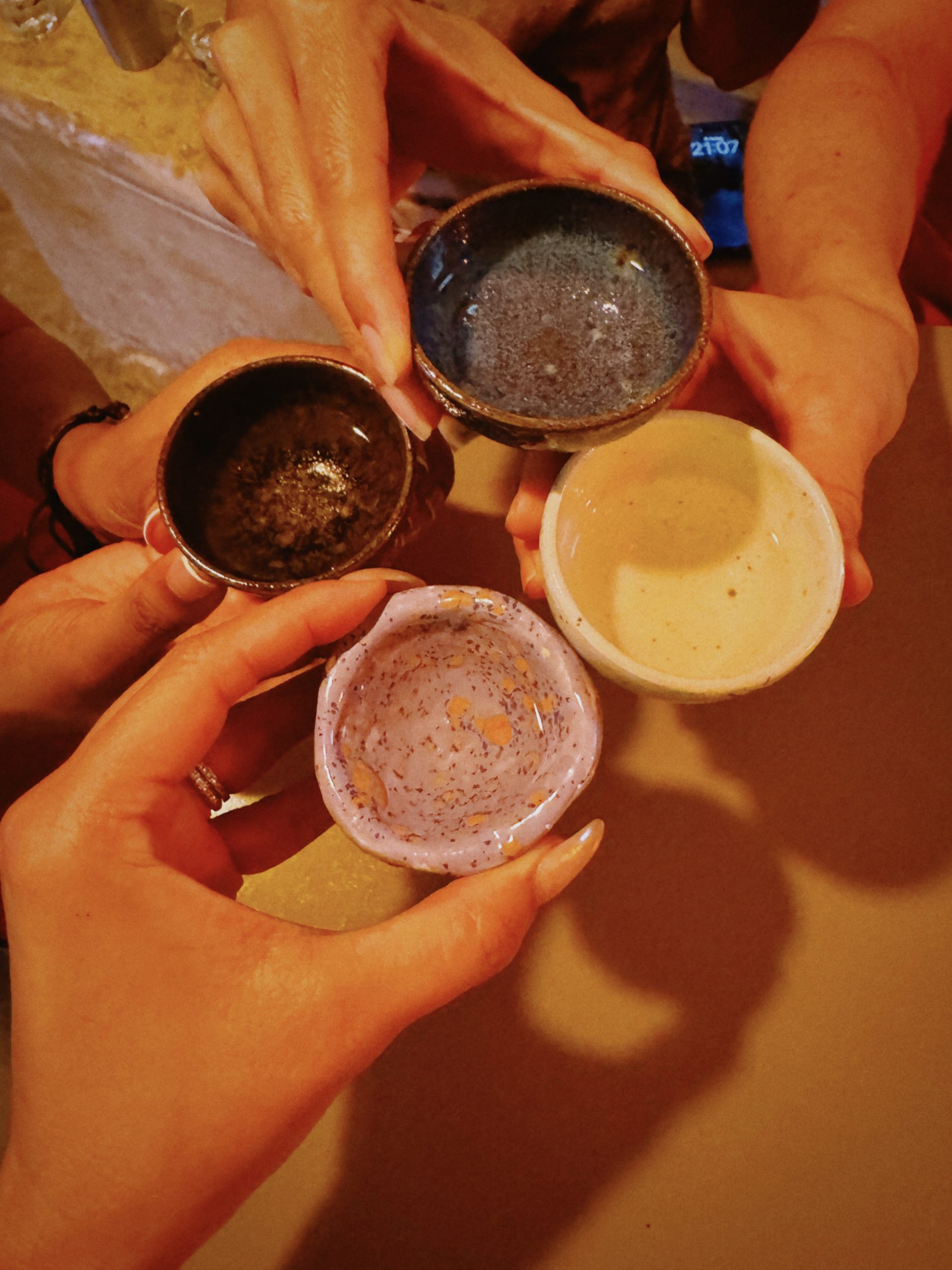 Private group raising handmade pottery bowls during a mezcal tasting in Tulum